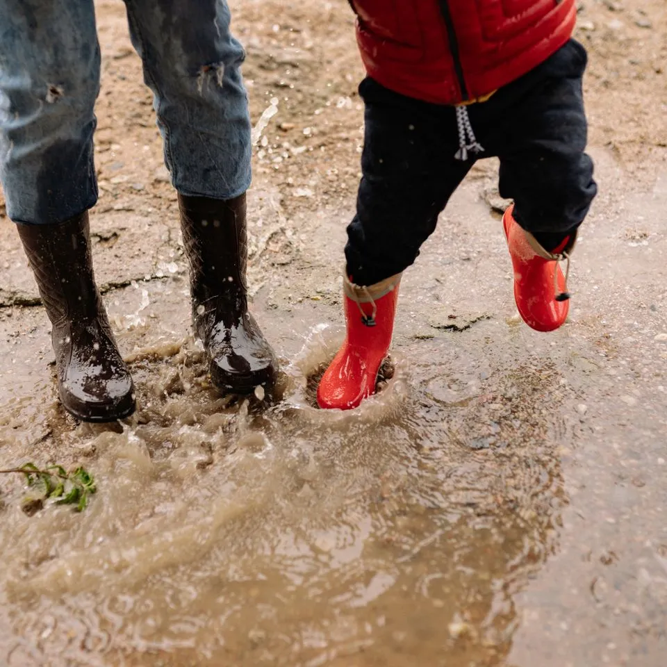 Kids in rubber boots jumping in a puddle